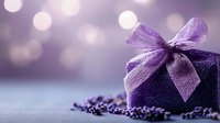 Purple gift box with delicate bow and scattered dried lavender flowers on soft bokeh background creates romantic atmosphere for special occasions.