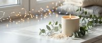 Cozy home interior with burning candle, eucalyptus branches and warm fairy lights creating peaceful hygge atmosphere for relaxation and wellness.