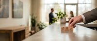 Hand placing wooden blocks with star rating symbols on office desk for customer feedback and quality evaluation in modern workplace setting.