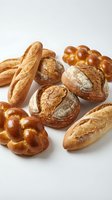 Assorted freshly baked artisan breads including baguettes, round loaves, and braided rolls arranged on white background for bakery, food service, and culinary projects.