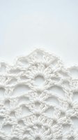White crochet lace pattern with intricate stitches on neutral background for crafting and textile design projects.