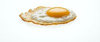 Crispy fried egg with golden yolk isolated on white background for breakfast menu design and culinary projects.