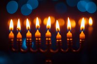 Glowing Hanukkah menorah candles with blue bokeh background creating festive holiday atmosphere for Jewish celebration.