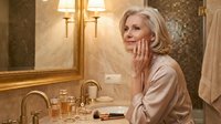 Elegant mature Caucasian woman applying skincare in luxurious bathroom mirror reflection. Anti-aging beauty routine, wellness lifestyle concept.