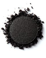 Dark charcoal eyeshadow powder with scattered crumbs on white background, isolated makeup cosmetic product for beauty and fashion design.