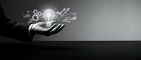 Businessman hand holding glowing lightbulb with growth charts and gears icons, representing innovation, strategy and business development concepts for corporate success.
