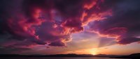 Dramatic sunset sky with vibrant pink and purple clouds over mountain silhouettes creating stunning natural landscape for backgrounds and travel content.