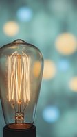 Vintage Edison bulb with glowing filament against soft bokeh lights background creating warm atmospheric lighting for interior design concepts.