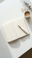 Minimalist workspace with open notebook, golden pen, coffee cup and eucalyptus branch on white desk. Clean aesthetic for productivity and planning concepts.