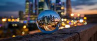 Crystal ball reflecting illuminated cityscape at dusk with blurred urban lights and skyscrapers in background, suitable for business, technology, and vision concepts.