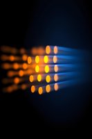 Glowing orange light dots in rows against dark blue background create abstract pattern with selective focus and bokeh effect for technology concepts.
