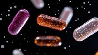 Glittering capsules with sparkles floating in dark space against black background, pink and orange medicine pills with shimmering effect for pharmaceutical design.
