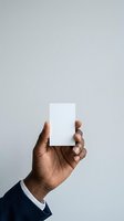 Male hand with medium skin tone holding blank white card against neutral background, suitable for business branding, marketing mockups, and corporate identity design projects.