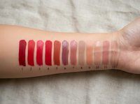 Lipstick color swatches on woman arm showing red pink nude shades makeup cosmetics palette testing beauty products for color matching selection.