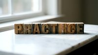 Wooden letterpress blocks spelling PRACTICE on white surface near window with natural lighting for business and education concepts.