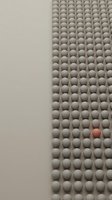 Minimalist abstract composition with gray spheres in geometric pattern and single pink sphere standing out from crowd representing uniqueness and individuality.