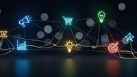 Digital network connecting glowing business icons including lightbulb, shopping cart, target, and growth chart on dark background with bokeh effects.