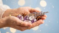 Hands holding healing crystals, dried lavender and star anise with magical sparkles for wellness, meditation and spiritual energy practices.