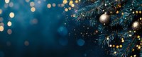 Christmas fir branches with silver baubles and golden bokeh lights on dark blue background, festive winter holiday panoramic composition.