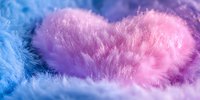 Soft fluffy heart shape in pink and blue cotton candy colors against dreamy pastel background creates romantic mood for valentines day designs and love concepts.