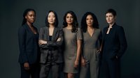 Diverse group of five professional women standing together against neutral background, wearing business casual and formal attire, representing corporate teamwork and leadership.