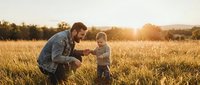 Father and toddler son bonding in golden wheat field during sunset, family outdoor lifestyle moment with warm natural lighting for parenting concepts.