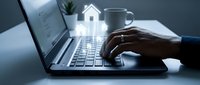 Professional working on laptop with house icon overlay representing real estate technology and property management solutions for modern business.