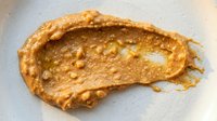 Creamy peanut butter spread on white surface, showing rich texture and natural color for food photography, cooking, nutrition, and culinary content.