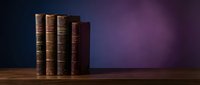 Stack of vintage leather-bound books on wooden table against purple gradient background. Classic literature collection for education, library, study concepts.