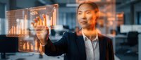 Asian businessman in suit analyzing financial data on transparent digital interface with growth charts and statistics in modern office environment.