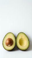 Fresh ripe avocado cut in half showing green flesh and brown pit on clean white background for healthy cooking and nutrition concepts.