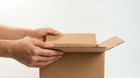 Hands opening brown cardboard delivery box on white background. Package unboxing concept for e-commerce shipping and online shopping experiences.
