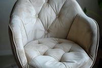 Elegant tufted armchair in soft cream velvet upholstery with deep button details and curved backrest, showcasing luxurious furniture craftsmanship and interior design.