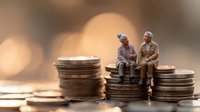 Senior couple sitting on stacks of coins, retirement savings concept with elderly miniature figures against warm bokeh background, financial planning theme.