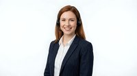 Professional Caucasian businesswoman with headset smiling in pinstripe suit jacket on white background for customer service and corporate communications.