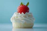 Fresh strawberry cupcake with swirled white frosting on blue background, perfect for dessert menu, bakery promotion, or food blog.