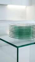 Stack of transparent glass plates arranged on a glass shelf in bright, minimalist interior space. Isolated glassware suitable for design, product mockups, and commercial applications.