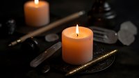 Burning candles with mystical ritual tools including crystals, wands and ceremonial objects on dark surface for spiritual practices and meditation.