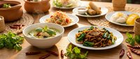 Asian cuisine spread featuring stir-fried noodles, soup, and fresh vegetables on wooden table for restaurant menus, food blogs, and culinary publications.