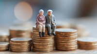 Elderly couple miniature figures sitting on stacked coins, representing retirement savings, pension funds, and financial security in senior years.