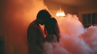 Romantic couple silhouette embracing in dramatic smoke atmosphere with warm orange lighting creating intimate mood for wedding or love concepts.
