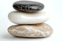Balanced stack of three smooth zen stones in black, white and beige colors on white background, symbolizing harmony, meditation and wellness.