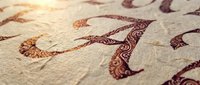 Ornate decorative letter A with intricate floral patterns and swirls embossed on textured paper surface for elegant typography and calligraphy projects.