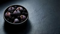 Dark figs and blackberries arranged in black bowl on slate surface, fresh organic produce for culinary and food styling projects.