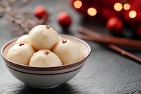 White steamed buns with sesame seeds in ceramic bowl on dark stone background with red Christmas ornaments and bokeh lights, Asian fusion holiday food.