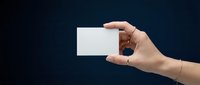 Female hand holding a blank white card against dark blue background, copy space for branding, business or personal identity design.