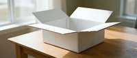 Open white cardboard shipping box on wooden table near window with natural light for packaging delivery and moving supplies.