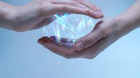 Two hands holding glowing holographic crystal with rainbow light effects against blue background. Concept for technology, innovation, energy, and future solutions.