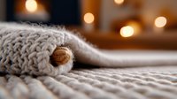 Cozy winter composition with warm knitted sweater and wooden button detail against blurred bokeh lights, creating soft atmospheric mood for seasonal design.