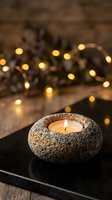 Stone candle holder with burning tea light on slate board creating warm ambiance with fairy lights and rustic wooden background for home decor and relaxation.